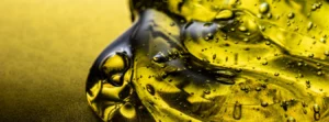A macro shot of thick, golden-yellow liquid with air bubbles, appearing like a gel or Lubricant oil.